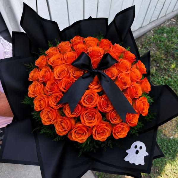 Bouquet of orange roses wrapped in black paper with a black ribbon