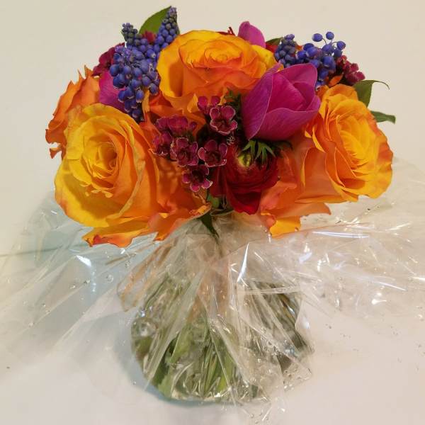 Bouquet of orange and yellow roses with purple accents in clear wrap