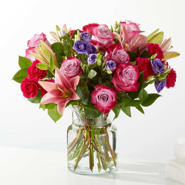 Bouquet of pink and red roses with lilies in a clear glass vase