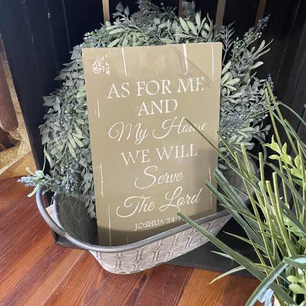 Decorative greenery arrangement in a metal basket with a scripture sign