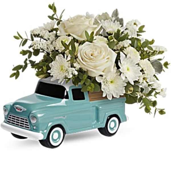 White roses and daisies arranged in a turquoise toy truck