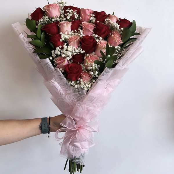 Bouquet of red and pink roses wrapped in pale pink paper