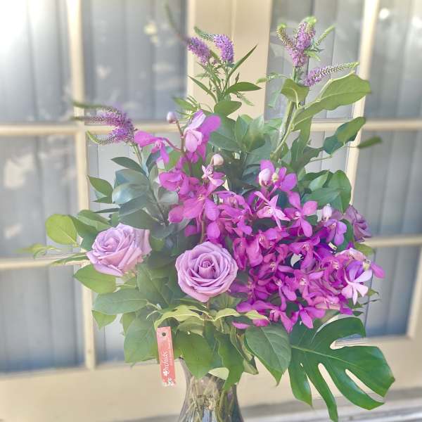 Pink roses and purple orchids in a glass vase