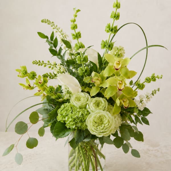 Green and white floral arrangement in a clear glass vase
