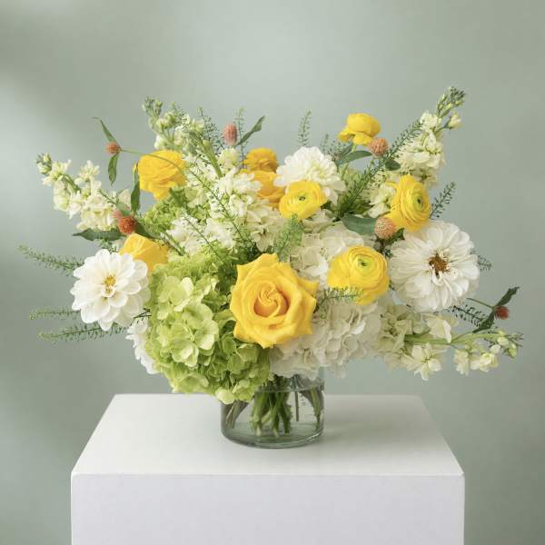 Yellow and white flowers arranged in a clear glass vase
