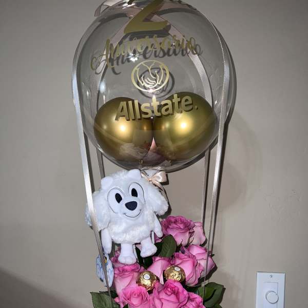 Pink roses with a plush dog and gold balloons in a clear balloon topper