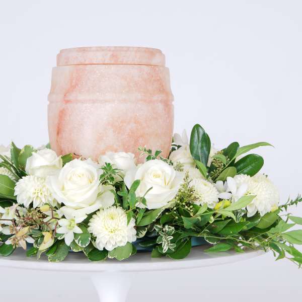 White rose and chrysanthemum arrangement around a peach urn