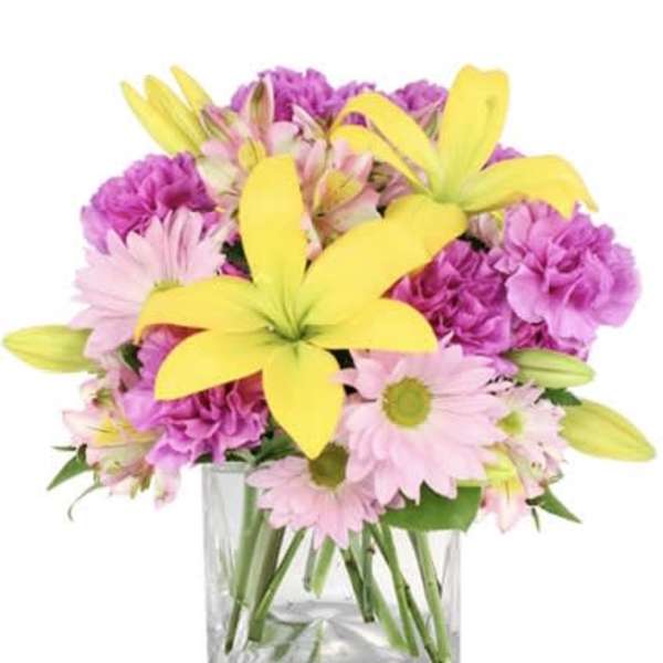 Pink and purple flowers with yellow lilies in a clear glass vase