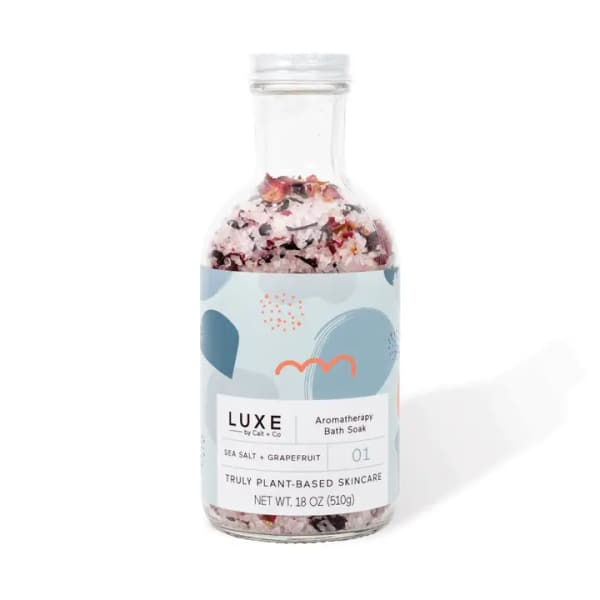 Bottle of aromatherapy bath soak with pink salt and dried petals