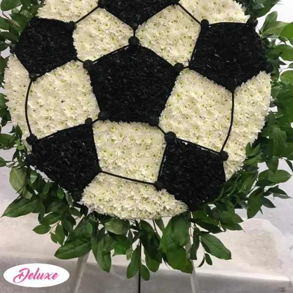 Soccer ball floral tribute on a stand with white and black flowers