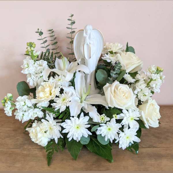 White floral arrangement with an angel figurine centerpiece