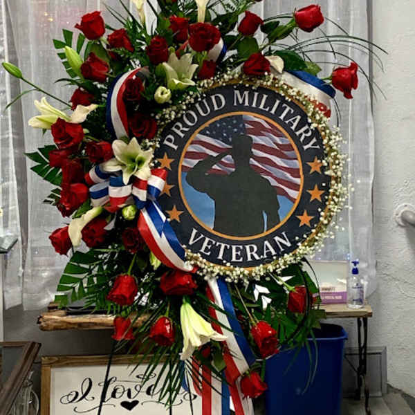 Standing wreath with red roses, white lilies, and a veteran tribute sign