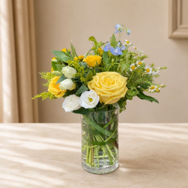 Yellow and white flowers arranged in a clear glass vase