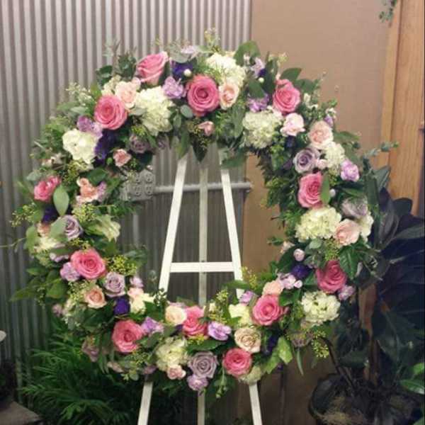 Large floral wreath on a white easel with pink, white, and purple flowers