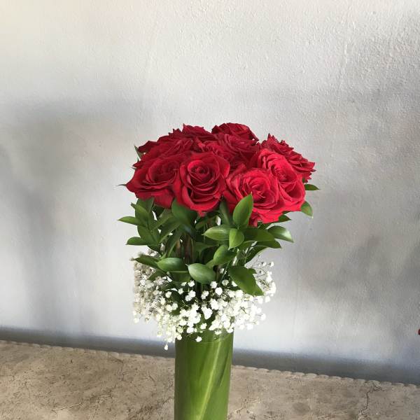Red roses in a tall green vase with white baby's breath