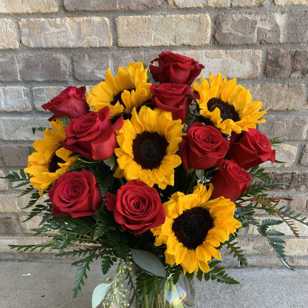Bouquet of red roses and yellow sunflowers in a glass vase