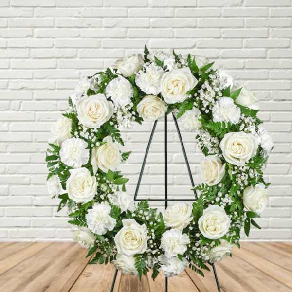White floral wreath on a black stand
