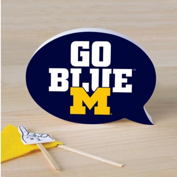 Blue speech bubble sign with "GO BLUE M" text and a small yellow pennant