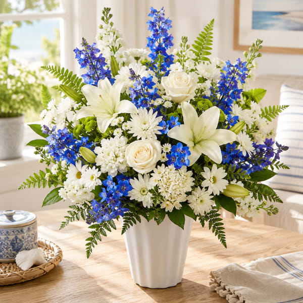 White and blue mixed flower arrangement in a white vase
