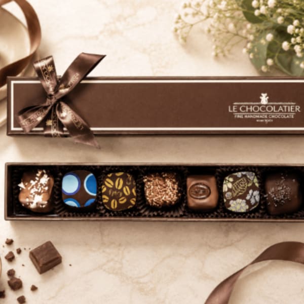 Box of assorted chocolates with a ribbon bow and open tray