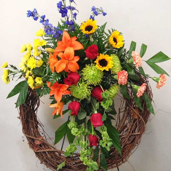 Colorful floral wreath with roses, lilies, sunflowers, and blue delphinium