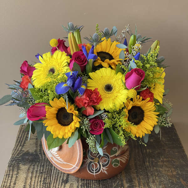 Bright mixed bouquet with sunflowers, gerbera daisies, roses, and irises in a decorative pot