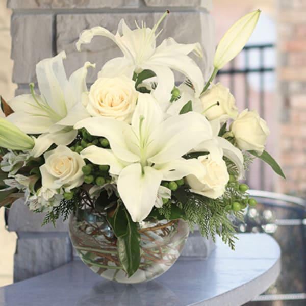 White lilies and cream roses arranged in a glass vase