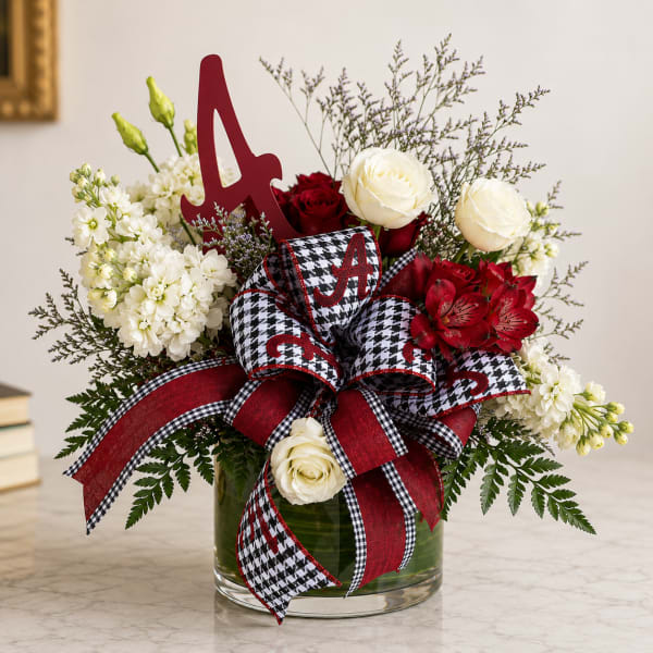 Red and white floral arrangement in a glass vase with a large ribbon and letter A