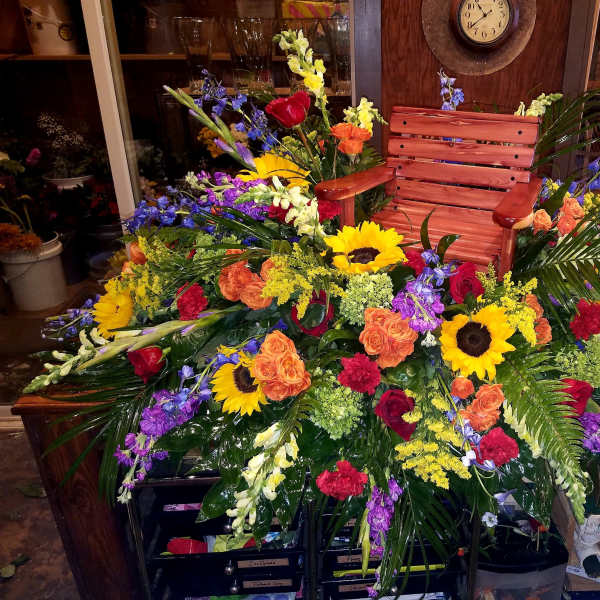 Large colorful floral arrangement with sunflowers and roses around a wooden chair