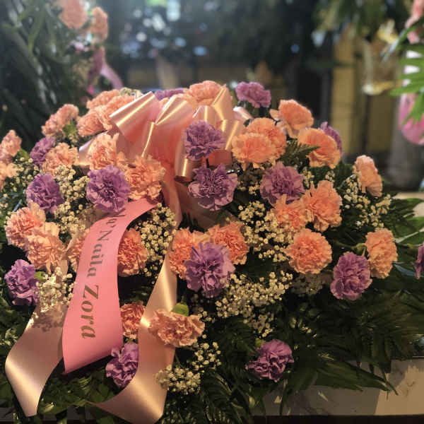 Large floral arrangement of pink and purple carnations with a satin ribbon