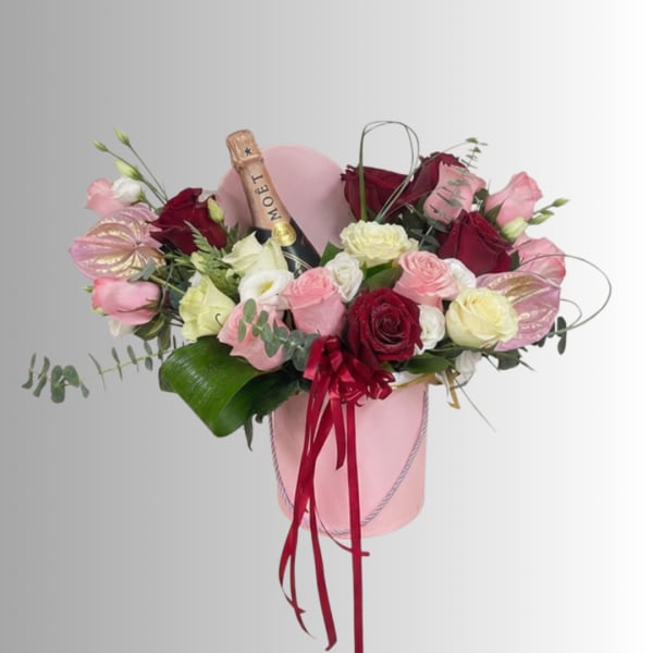Pink and red rose arrangement in a pink hatbox with a champagne bottle