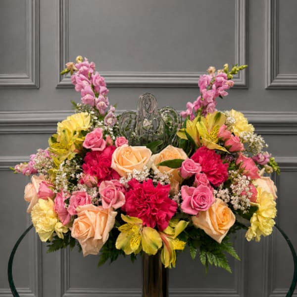 Large floral arrangement with pink, peach, and yellow flowers in a vase