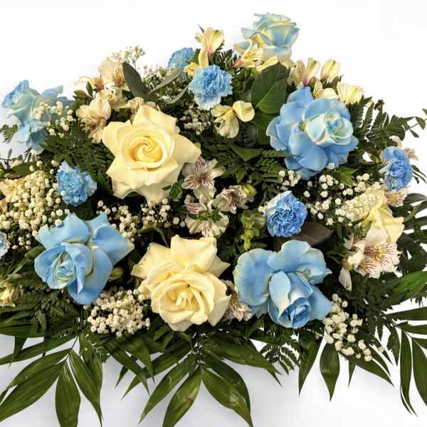 Large floral arrangement with blue and cream roses and small white filler flowers
