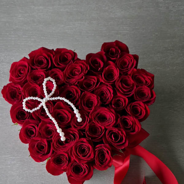 Heart-shaped bouquet of red roses with a pearl accent and red ribbon