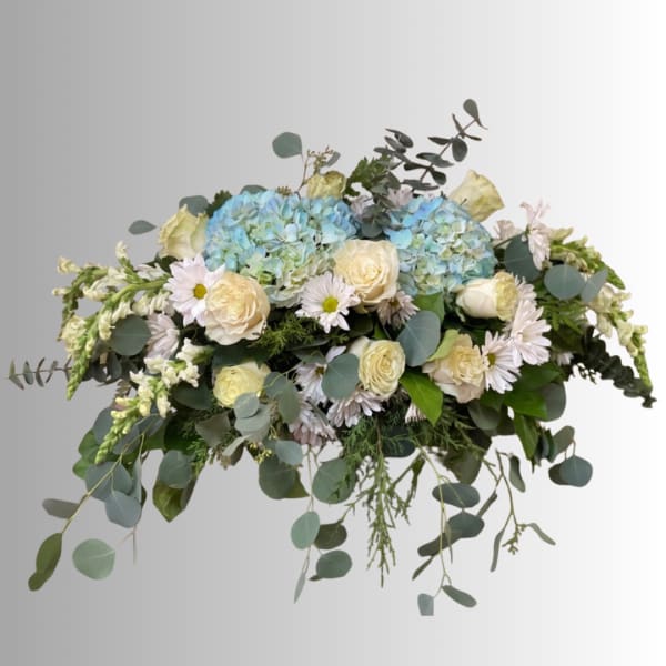 Blue hydrangeas and cream roses in a low floral arrangement