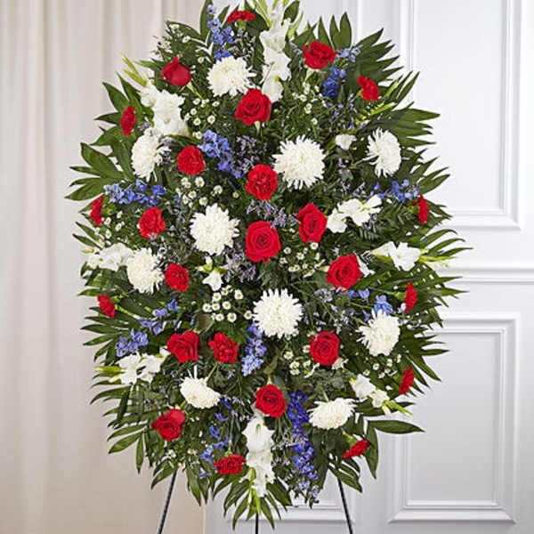 Standing floral spray with red roses, white mums, and blue flowers
