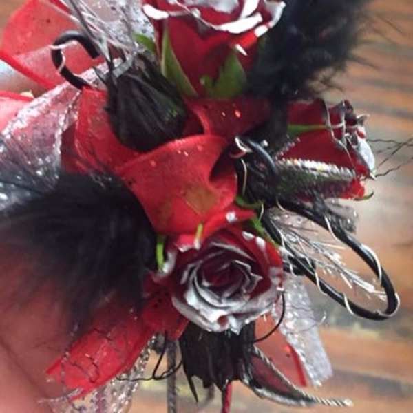 Small red and white rose corsage with black feathers and ribbon