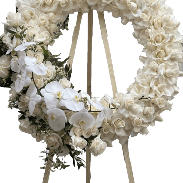 White floral wreath on a wooden easel with orchids and roses