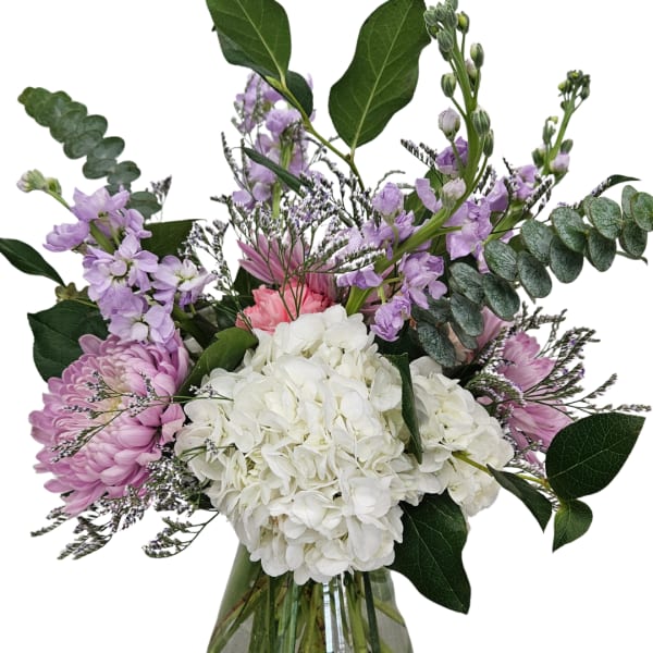 Bouquet of white hydrangea, pink chrysanthemums, and lavender flowers in a glass vase
