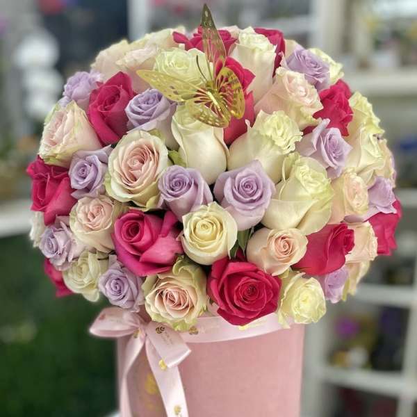 Round hatbox of pink, white, cream, and lavender roses with a gold butterfly accent and ribbon bow.
