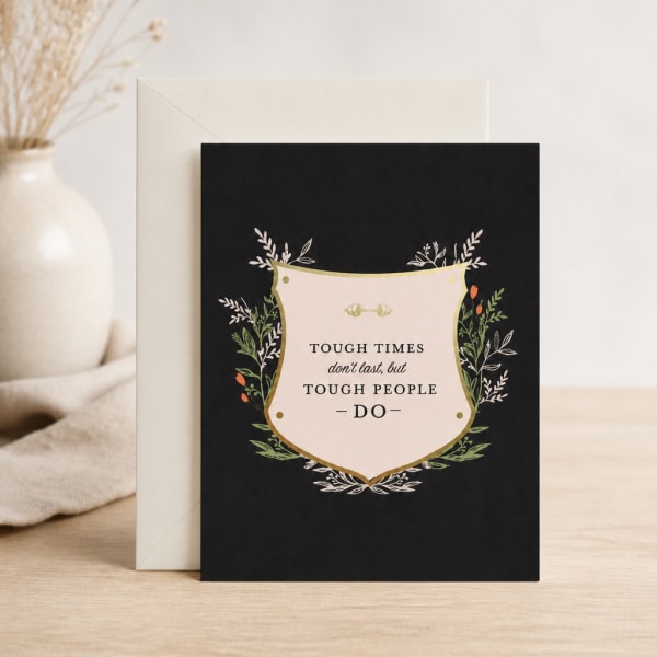 Black greeting card with a motivational quote and floral border, leaning against an envelope