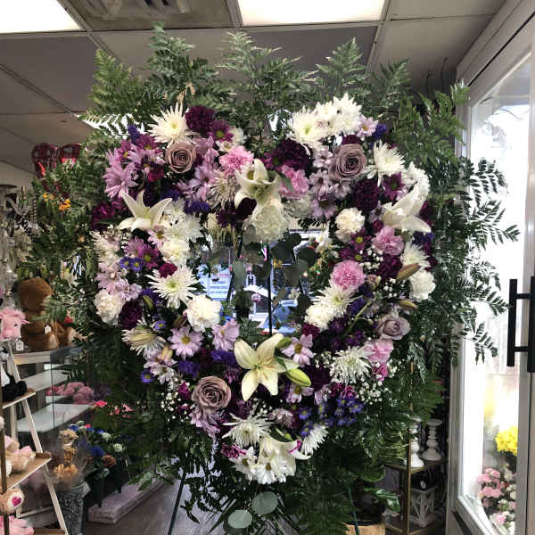 Large heart-shaped floral wreath on an easel with white, pink, and purple flowers