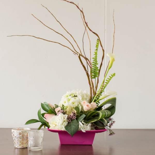 Modern floral arrangement in a pink container with white and blush blooms