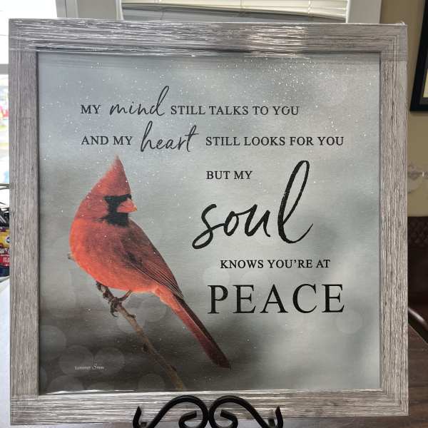 Framed memorial sign with a red cardinal and peace message