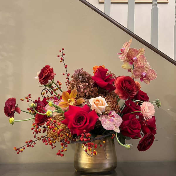 Mixed red and pink flower arrangement in a gold vase