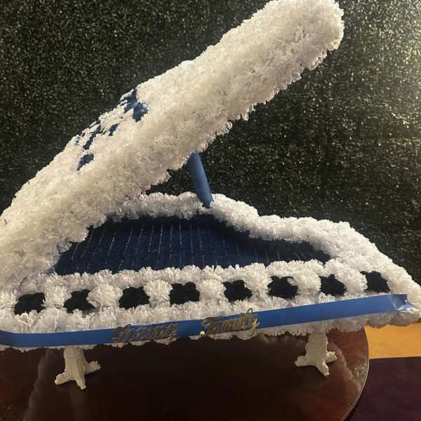 White floral casket spray with blue ribbon accents