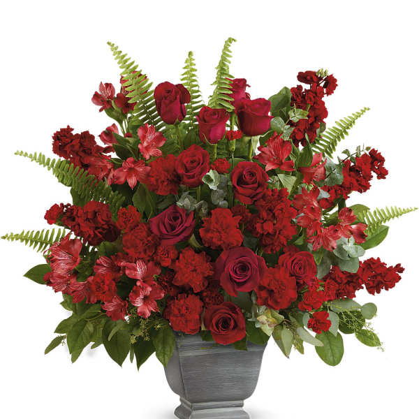 Red roses and carnations arranged in a gray urn vase