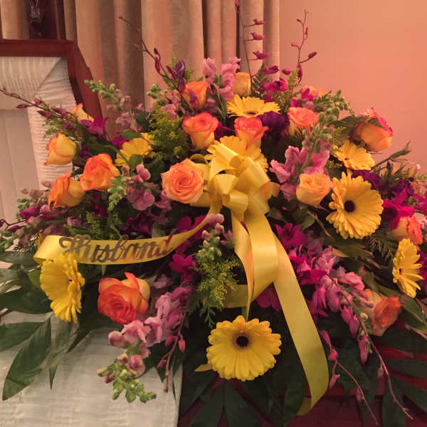 Large floral spray with yellow ribbon and mixed pink, orange, and yellow blooms