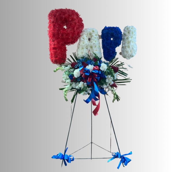 Floral standing tribute spelling "PAPA" with red, white, and blue flowers