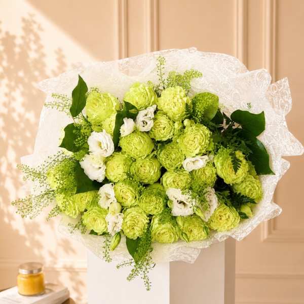 Bouquet of lime green and white flowers wrapped in white lace paper